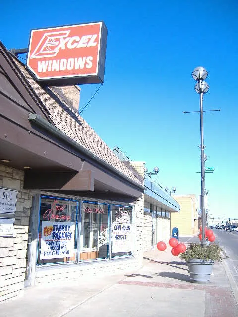 The Excel storefront during an open house, the red EXCEL WINDOWS sign up top and balloons on the sidewalk.