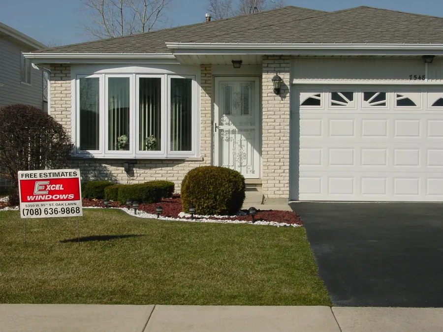 A finished bay-window job with the old red Excel Windows yard sign staked in the lawn.