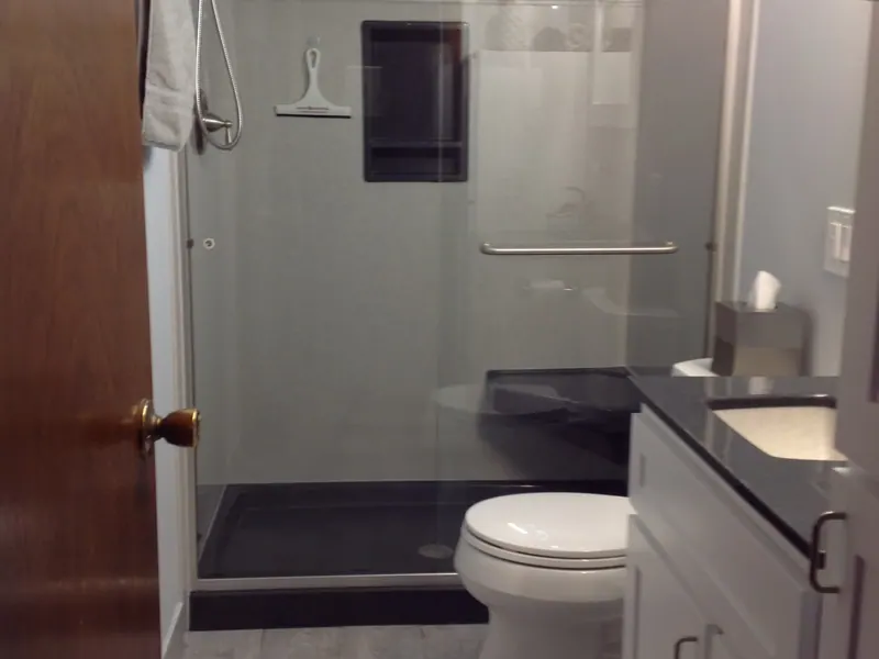 Finished walk-in shower with gray solid-surface walls, a low-threshold base, and a grab bar, an Excel install in the south suburbs